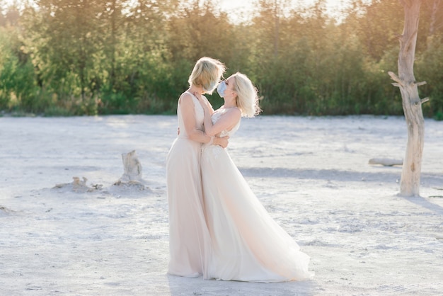 Lesbian couple wedding on sand wearing masks