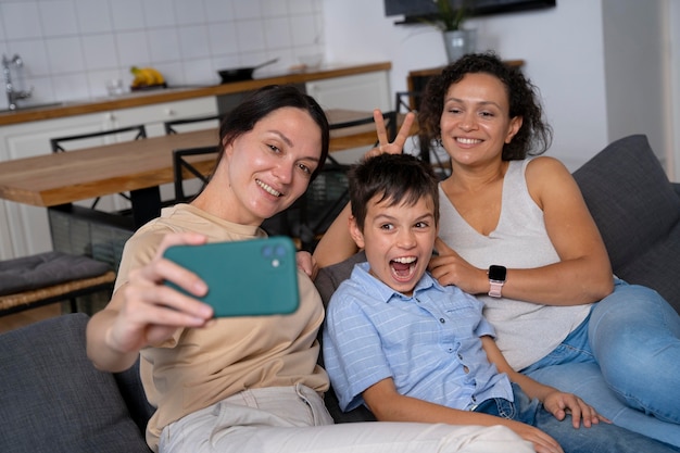 Photo lesbian couple with their son taking a selfie