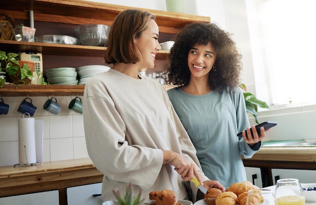 lesbian couple and women with phone and cooking with happiness in kitchen for breakfast and nutrition in morning food people and smile with romance in home or face for wellness lgbt or love