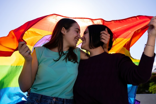 Foto ragazze lesbiche che si divertono a dipingersi e con la bandiera lgtb il giorno dell'orgoglio lgtb concept