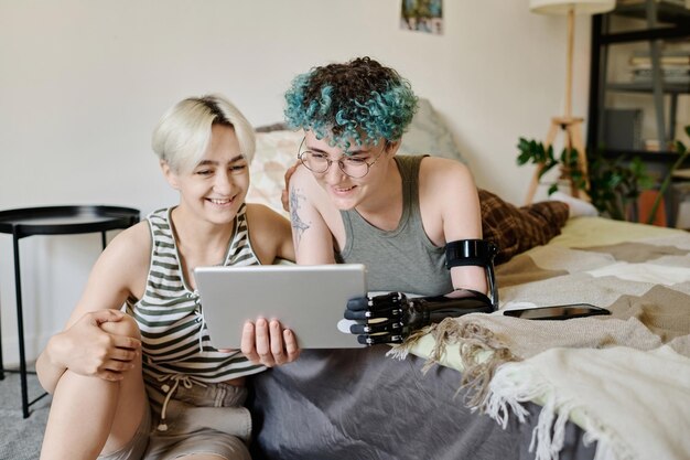 Lesbian girls watching video on digital tablet together in bedroom at home