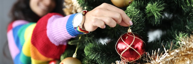 Lesbian woman hanging christmas balls on tree and smiling close-up