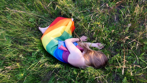 Lesbian woman lying naked on lgbt flag on green grass support of nontraditional orientation in the m