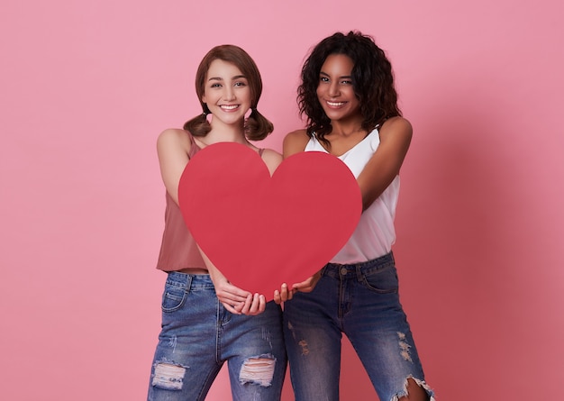 Lesbisch koppel staan en hand met rood hart voor Valentijnsdag.