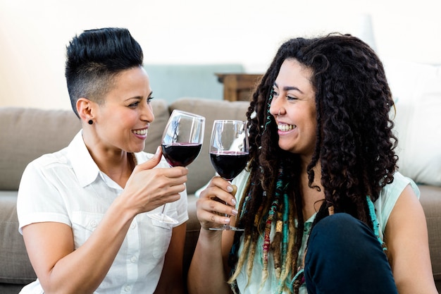Lesbisch paar dat en wijnglazen glimlacht roostert