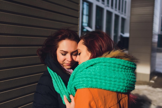 Lesbisch paar jonge vrouwen meisje draagt een warme hoed meisje sluit de oren van een vriend met haar handen in handschoenen in de koude winter