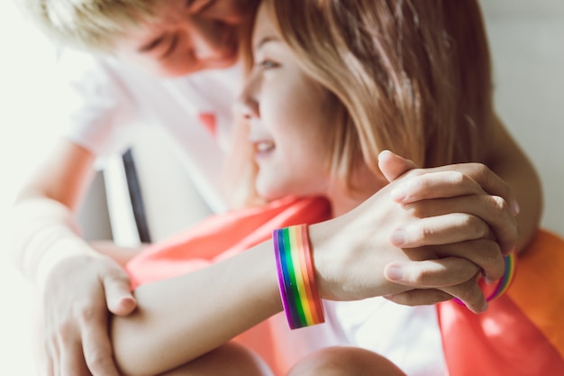 Lesbisch stel bedekt door LGBT-vlag en houdt haar paarhanden vast.