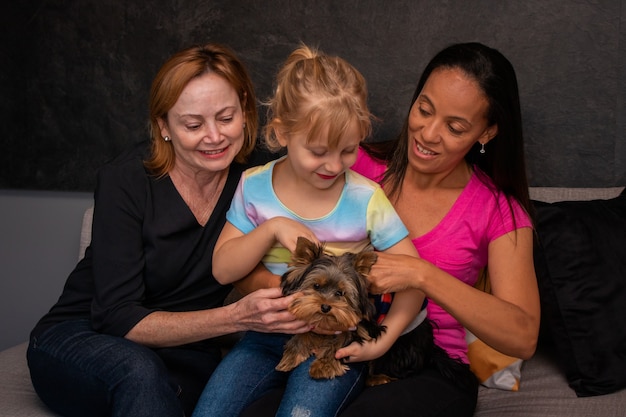 Foto lesbische familie en hun dochter zittend op de bank met hun hond