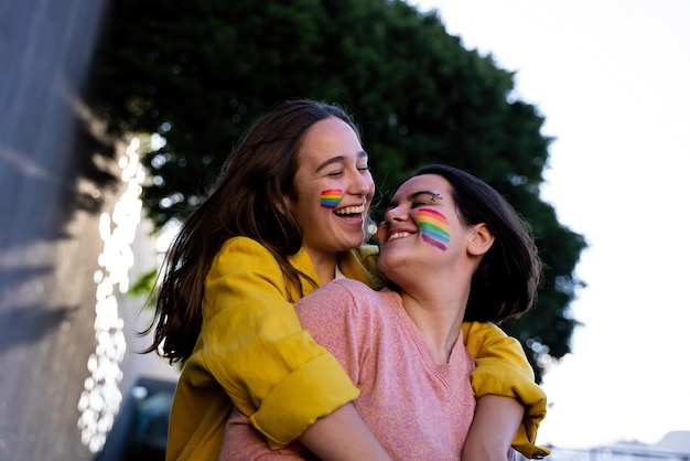 lesbische meisjes die plezier hebben met het schilderen van zichzelf en met de lgtb-vlag op pride-dag lgtb-concept