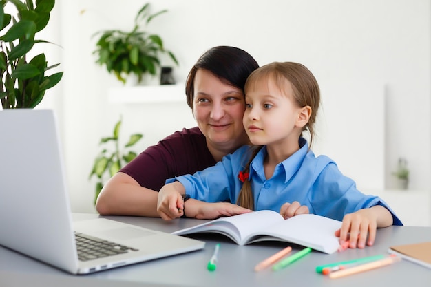 Lessen op afstand. Het kind lacht vrolijk en krijgt kennis op afstand. Klein meisje studeert online leren vanuit huis. Onlineschool.