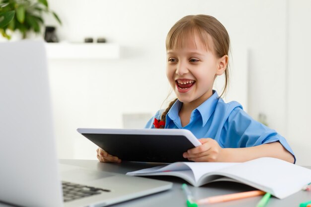 Lessen op afstand. Het kind lacht vrolijk en krijgt kennis op afstand. Klein meisje studeert online leren vanuit huis. Onlineschool.