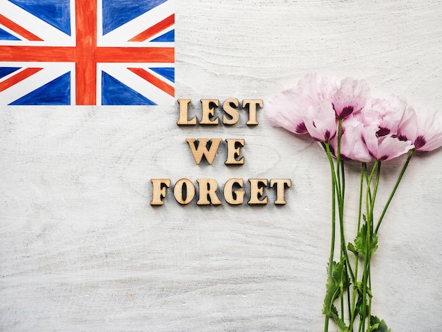 Lest we forget tekst naast britse vlag en bloemen