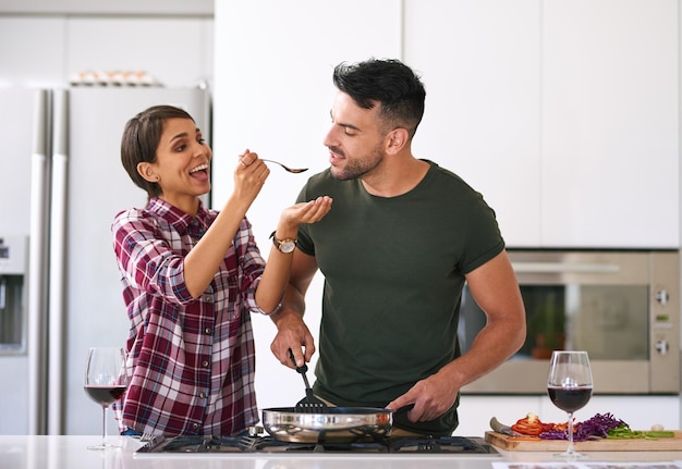 Fammi sapere cosa ne pensi foto ritagliata di una giovane coppia attraente che cucina insieme in cucina a casa