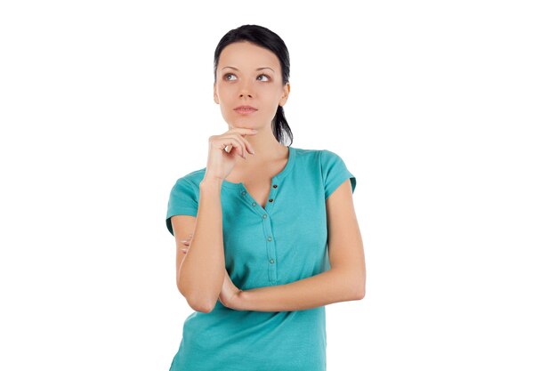 Let me think about this. Beautiful young woman thinking about something and holding hand on chin while standing isolated on white