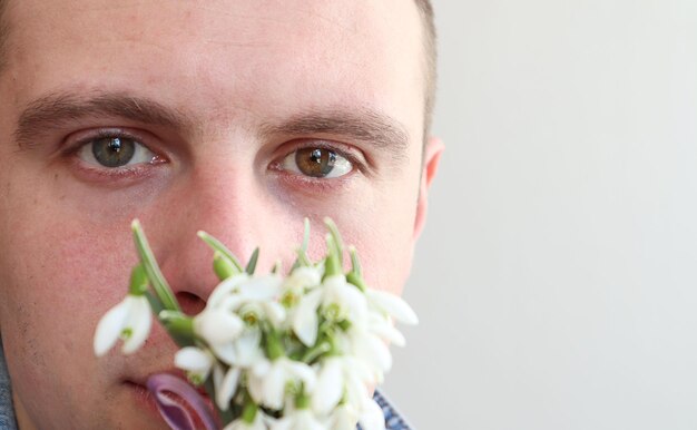 Let's congratulate your loved ones on the holiday closeup eyes of a man bokeh from a bouquet of snowdrops space for text