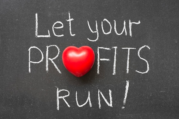 Let your profits run exclamation handwritten on chalkboard with heart symbol instead of O