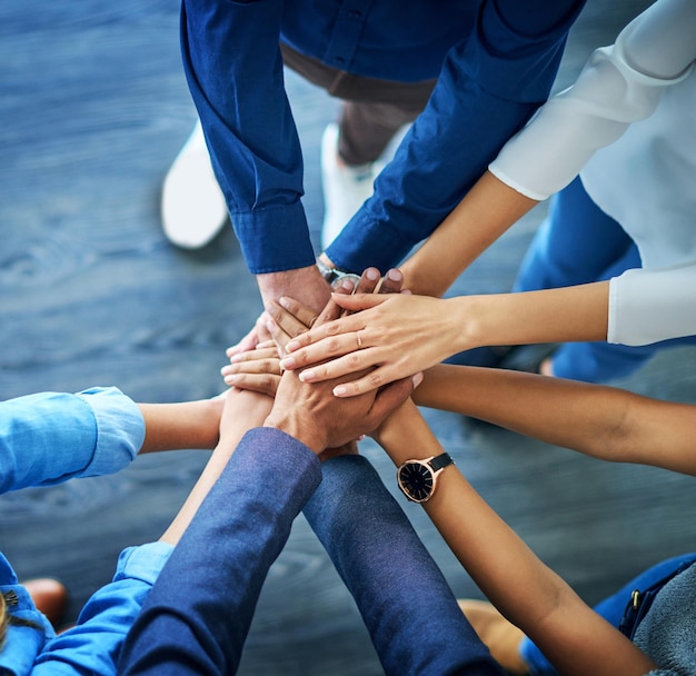 Photo lets awaken the team spirit high angle shot of a group unrecognizable businesspeople joining their hands together in unity