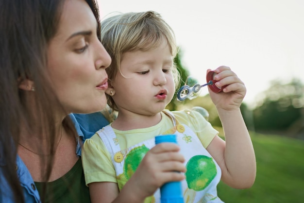 Lets blow a big bubble together Shot of a mother and her little daughter blowing bubbles outdoors