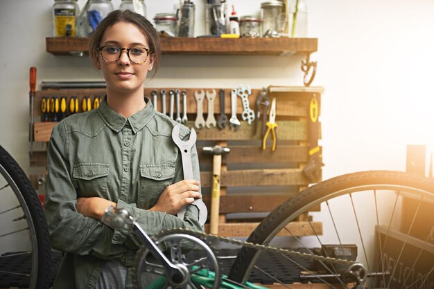自転車を再び真新しい状態に戻しましょう自転車修理店で働く自信のある若い女性の肖像画