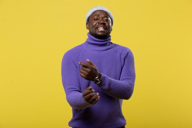 Lets sing. Cheerful male person keeping smile on his face while posing over yellow wall