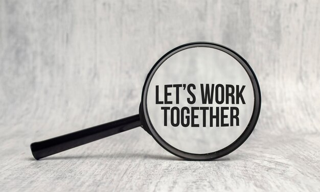 lets work together word on magnifier on wooden background