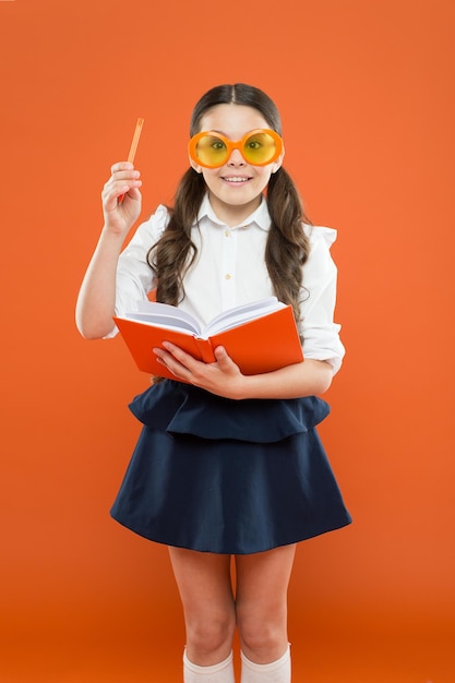 Lets write this idea children literature get information from book happy school girl in uniform and party glasses small child with notebook literature lesson education writing in workbook