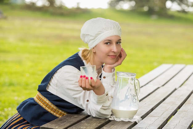 Letse vrouw in traditionele kleding met melkglas op de natuur