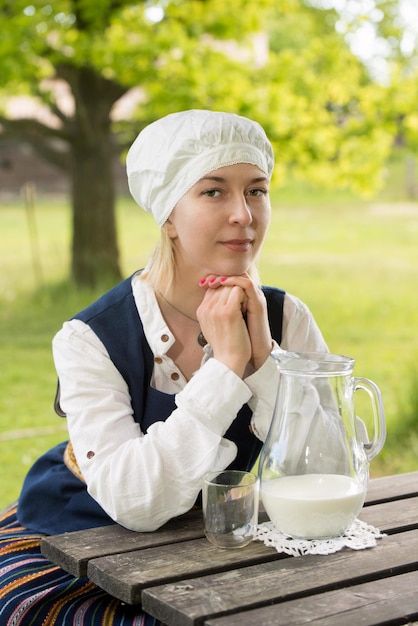 Letse vrouw in traditionele kleding met melkglas op de natuur