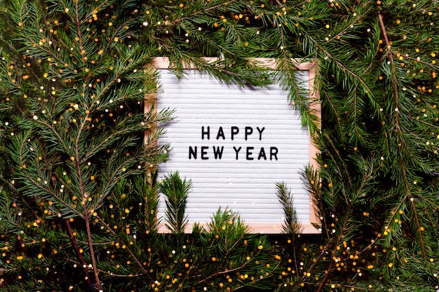 Foto lettera bordo capodanno e concetto di natale. decorazioni di natale del copyspace di vista orizzontale superiore e albero della pelliccia.