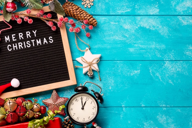 Letter board with words Merry Christmas, vintage clock and decorations on blue wooden table. Winter Christmas celebration concept. Free space for your text