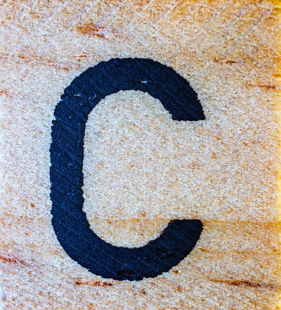 Letter C laser engraved on balsa wood macro close up texture detail