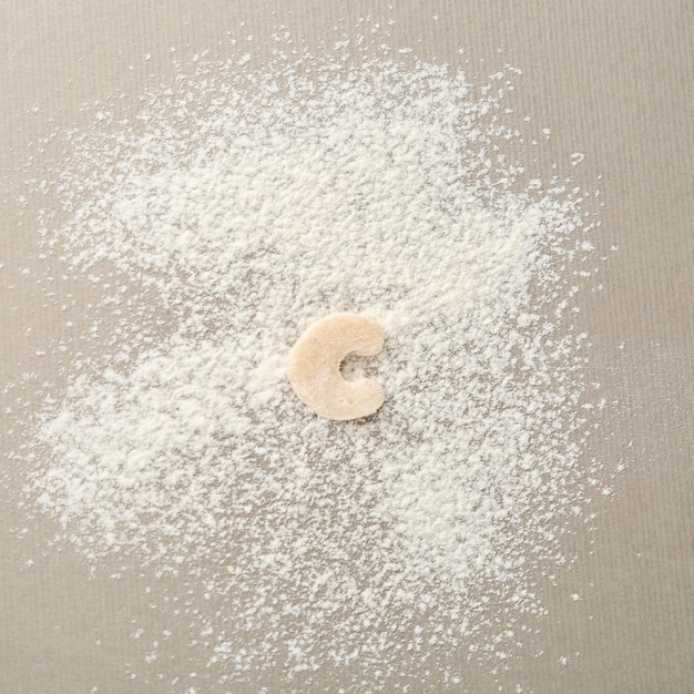 Letter C made of raw dough on flour