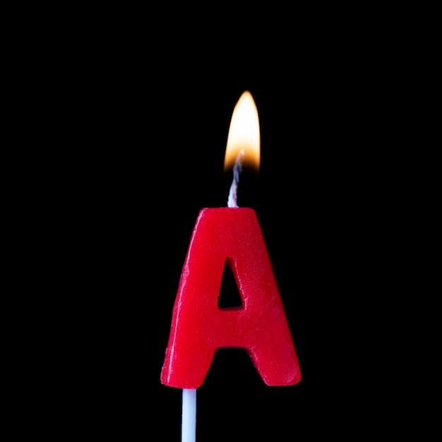 Photo letter a celebration birthday candle against a black background