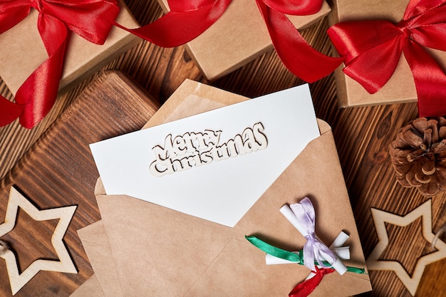 Letter in an envelope with the inscription merry christmas on the background of Christmas gift boxes