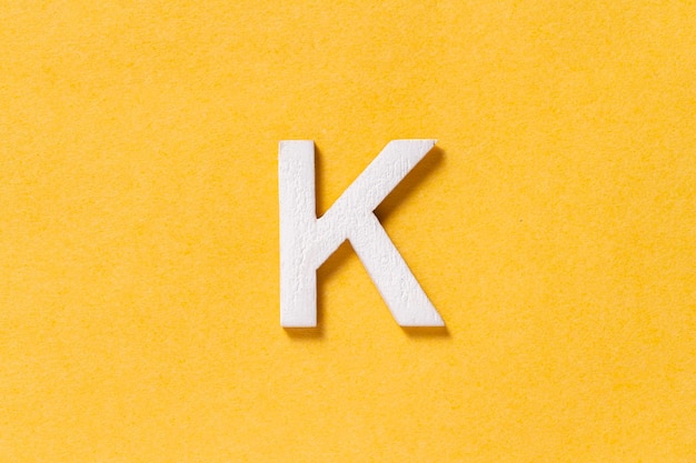Letter K van het alfabet geïsoleerd op gele achtergrond bovenaanzicht