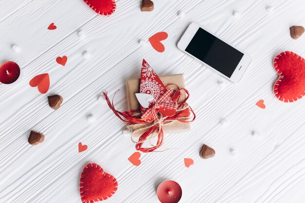 A letter of love, decorative hearts, gifts and smartphone on a white table for valentine's