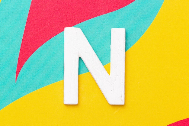 Photo letter n of the alphabet on colored background top view