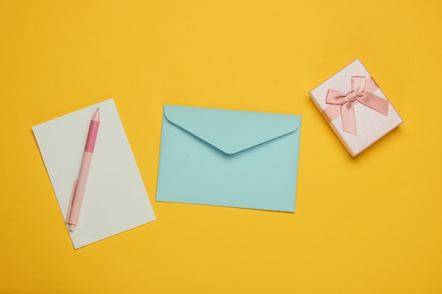 Letter to Santa. Envelope with letter and pen, box of gift on yellow background. Christmas Flat lay. Top view