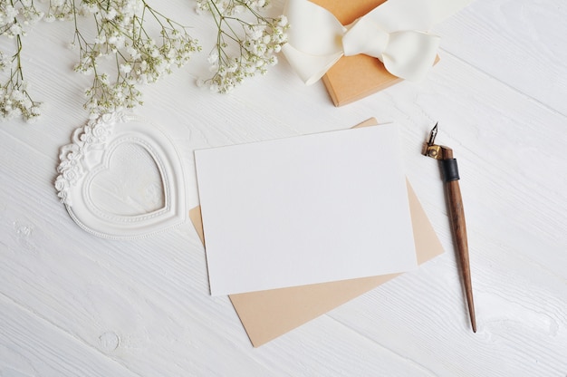 La lettera con una scatola dell'amore a forma di cuore giace su un tavolo di legno bianco con fiori di gypsophila