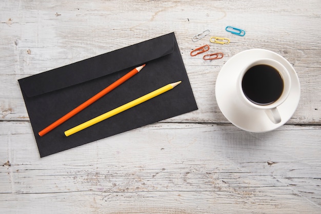 Letter with pencils and cup of coffee on table