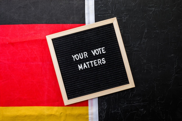 Photo letterboard sign with the words your vote matters with german flag on  black background