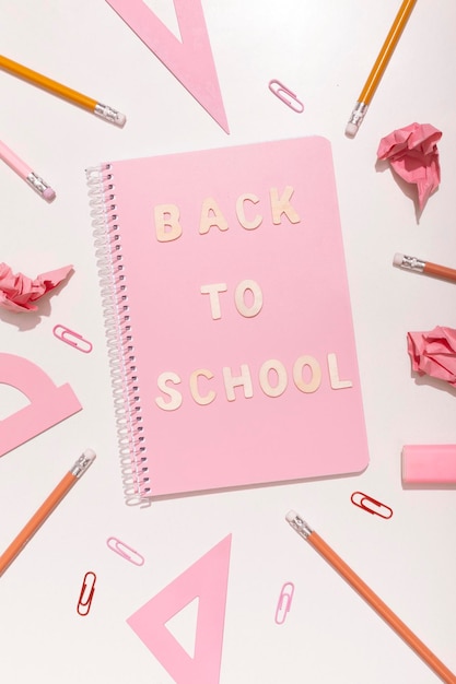 Lettering back to school on a pink background with school supplies