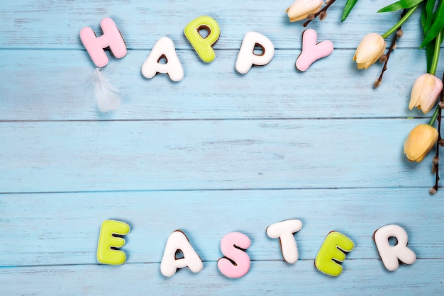 lettering from cookies happy easter on wooden blue background.