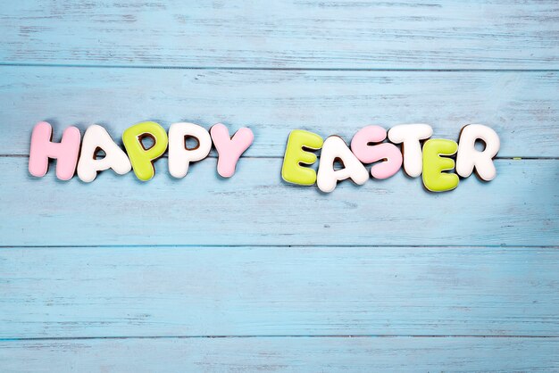 lettering from cookies happy easter on wooden blue background.