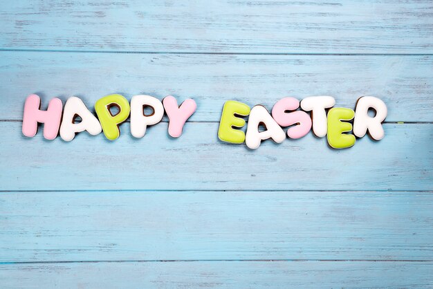 Lettering from cookies Happy Easter on wooden blue background.