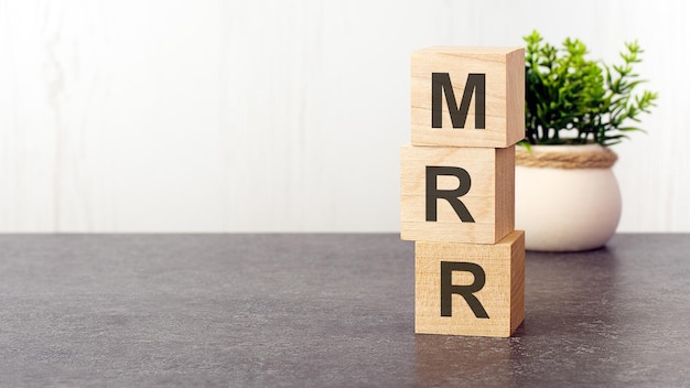 木製の立方体のMRRのアルファベットの文字緑の植物白い背景MRRは月間経常収益の略です