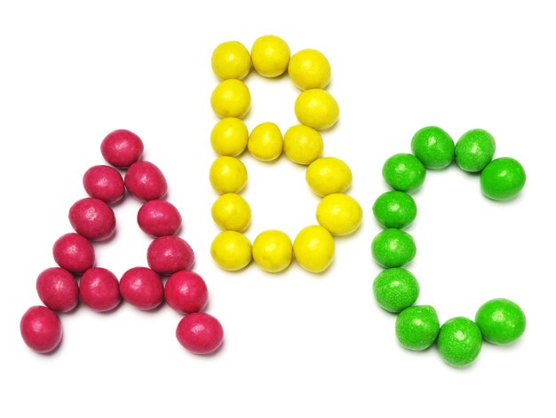 Letters A B and C from colored candy on white