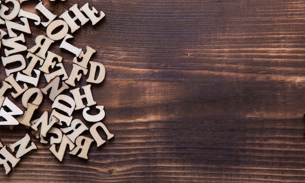Lettere dell'alfabeto inglese su uno sfondo di legno scuro. il concetto di educazione, giochi di parole, cucito. spazio per il testo
