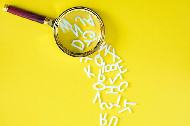 Letters English alphabet fallout magnifying glass, concept of knowledge and learning, on yellow background.