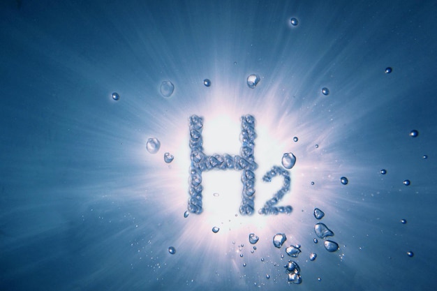 写真 太陽と光線の青い水の中の泡の多い水素h2の文字